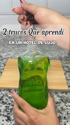 a person is holding a green liquid in front of a wooden cutting board with the words 2 trucos que arrendil en un hotel de lujo