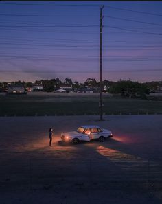 a person standing next to a parked car at night