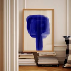 a blue painting sitting on top of a wooden floor next to a pile of books