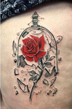 a woman's thigh with a rose in a glass case tattoo on her stomach