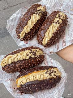 three chocolate donuts with peanut butter frosting on top and some wrappers around them