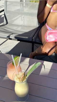 a woman sitting at a table with a drink in front of her on the beach