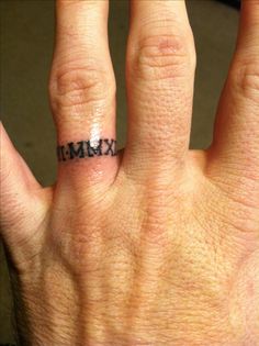 a person's hand with a ring on it and the word maximum written in black ink