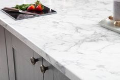 a white marble counter top with two candles and some strawberries on the plate next to it