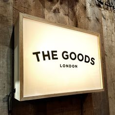 a sign that reads the goods london hanging on a wooden wall next to a clock