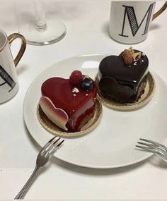 two heart shaped desserts on plates with forks