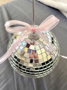 a glass ornament with a pink ribbon hanging from it