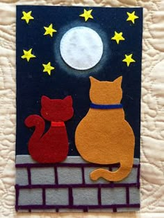 an orange cat and red cat sitting on top of a brick wall under the moon