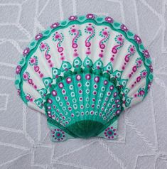 a green and white hand fan sitting on top of a bed next to a wall