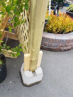 there is a wooden pole that has been placed in front of a planter and potted plants