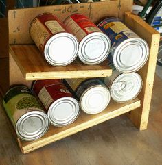 several cans of canned food are stacked on a wooden shelf