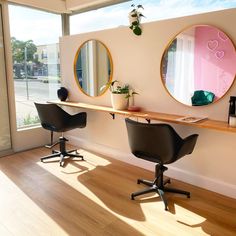 there are two chairs that are in front of the wall with mirrors and plants on it