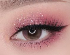 an eye with pink and white glitters on the lids, lashes and eyeshadow