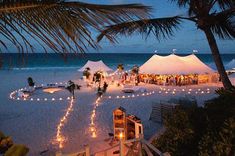 the beach is lit up with candles and lights for an outdoor party on the sand