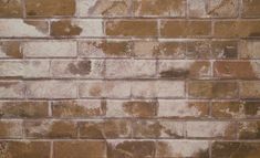 a brown brick wall with white patches of paint on the top and bottom part of it