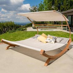 an outdoor daybed with canopy and pillows on the ground in front of a house