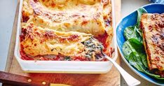 a casserole dish with spinach and cheese next to a salad on a cutting board