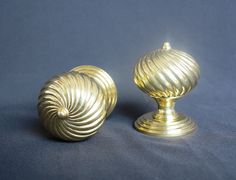 two golden knobs on a blue background, one has a spiral design and the other has a round shape