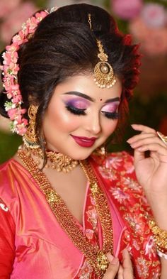 a woman in a red and gold outfit with flowers on her head, wearing jewelry