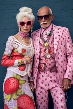 an older man and woman dressed up in matching outfits, standing next to each other