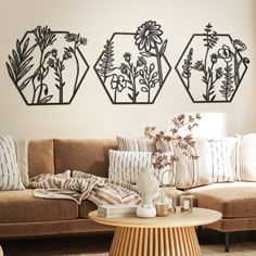 three metal flower vases sitting on top of a wooden table next to a couch