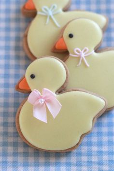 decorated cookies in the shape of ducks on a blue and white checkered tablecloth