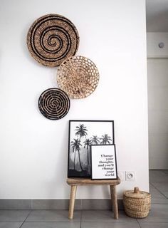 three baskets are hanging on the wall next to a small table with pictures and a basket