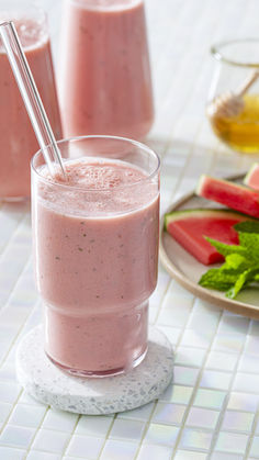 two glasses filled with watermelon smoothie next to sliced watermelon on a plate