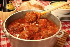 meatballs in tomato sauce being stirred with a wooden spoon into a pot on the table