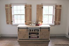 an empty kitchen with wooden shutters on the windows, and a counter in front of them