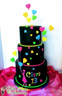 a three tiered black cake with hearts and balloons on the top is for a 13th birthday