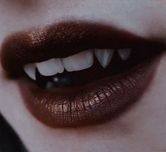 a woman's lips with white teeth and dark makeup