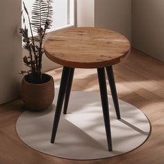 a wooden table sitting on top of a white rug next to a potted plant