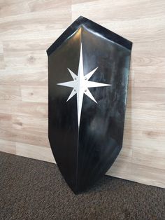 a black and white metal shield with a star on it's side against a wood wall