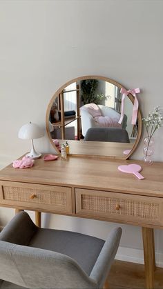 a mirror sitting on top of a wooden desk next to a chair and table lamp