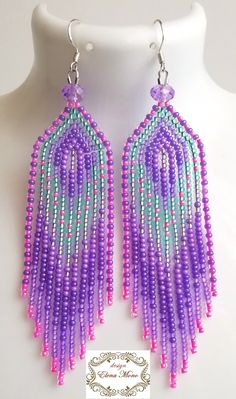 a pair of purple and green beaded earrings on a white mannequin dummy