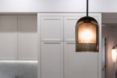 a light that is hanging from a ceiling in a room with white cabinets and cupboards