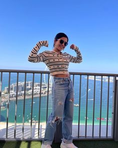 a woman standing on top of a balcony with her arms in the air and smiling