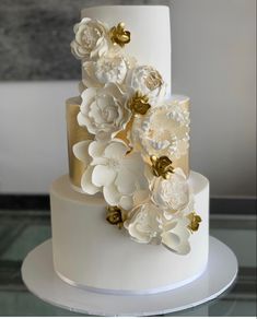 a white and gold wedding cake with flowers on top