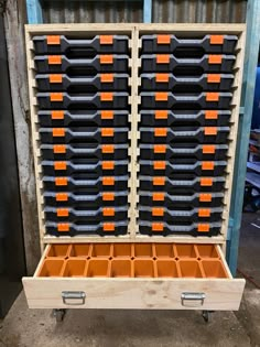 a large wooden box filled with lots of orange and black drawers next to a metal container