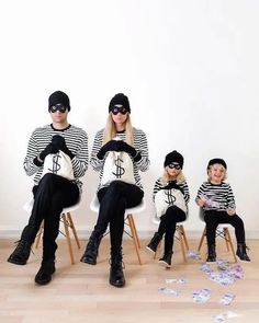 four people sitting on chairs wearing black and white striped sweaters, with money scattered around them