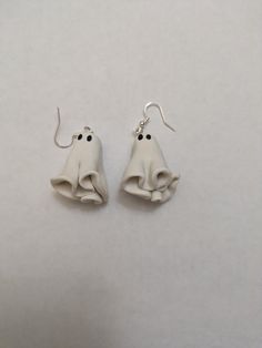 two white earrings with black eyes and one has a bell on it's ear