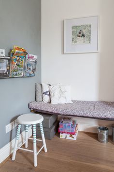 a room with a bed, stool and pictures on the wall