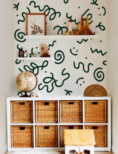 a white shelf with baskets on top of it in front of a wall painted with green paint