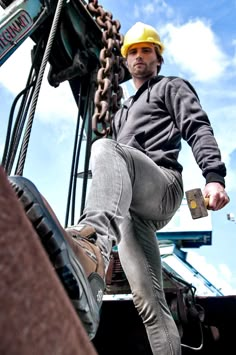 a man wearing a hard hat standing on top of a crane