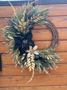 a wreath is hanging on the side of a wooden wall with pine cones and flowers