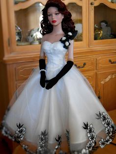 a doll in a white dress and black gloves