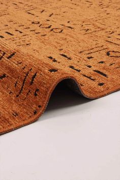 an orange rug with black writing on the bottom and bottom corner, in front of a white background