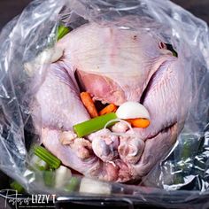 a turkey in a bag with carrots, celery and onions on it