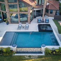 an aerial view of a house with a swimming pool and patio furniture in the foreground